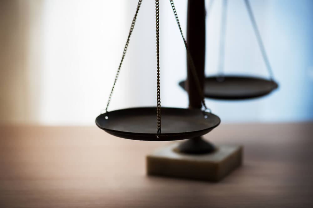 A close-up of a balance scale, with one empty pan in focus and the other blurred in the background, symbolizing justice or fairness—reflecting JEAR Logistics Core Values—on a wooden surface.